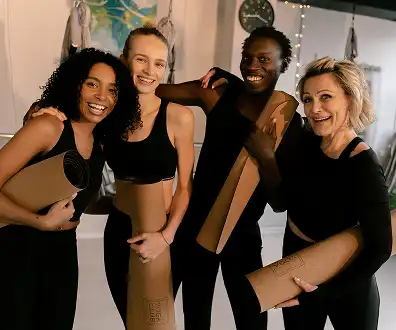 Group of people holding yoga mats and smiling in a fitness studio