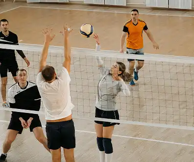 Players jumping and blocking during an indoor volleyball match