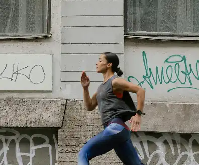 Person running past a graffiti-covered building in an urban setting